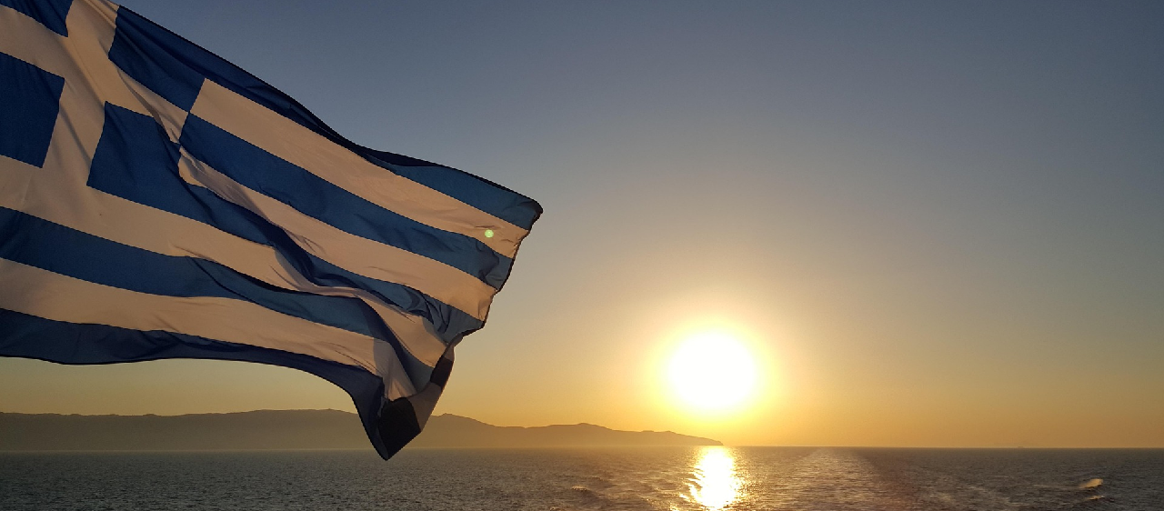 Flag of Greece waving above a greek sea